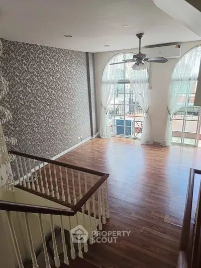 Spacious living room with elegant wallpaper and large windows for natural light.