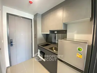 Modern compact kitchen with sleek cabinetry and stainless steel appliances in a stylish apartment.