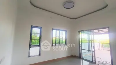 Spacious room with large windows and sliding glass door opening to a balcony.