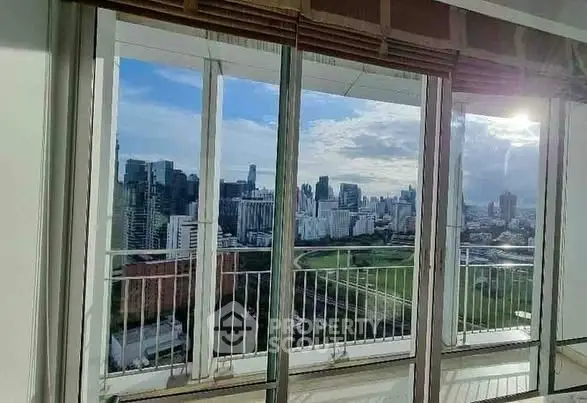 Stunning cityscape view from high-rise apartment balcony with large windows.
