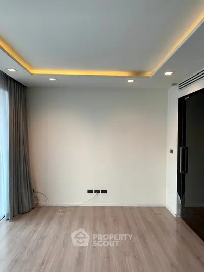 Spacious modern living room with elegant lighting and large window curtains.