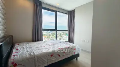Bright bedroom with large window offering stunning city views, modern decor, and cozy ambiance.