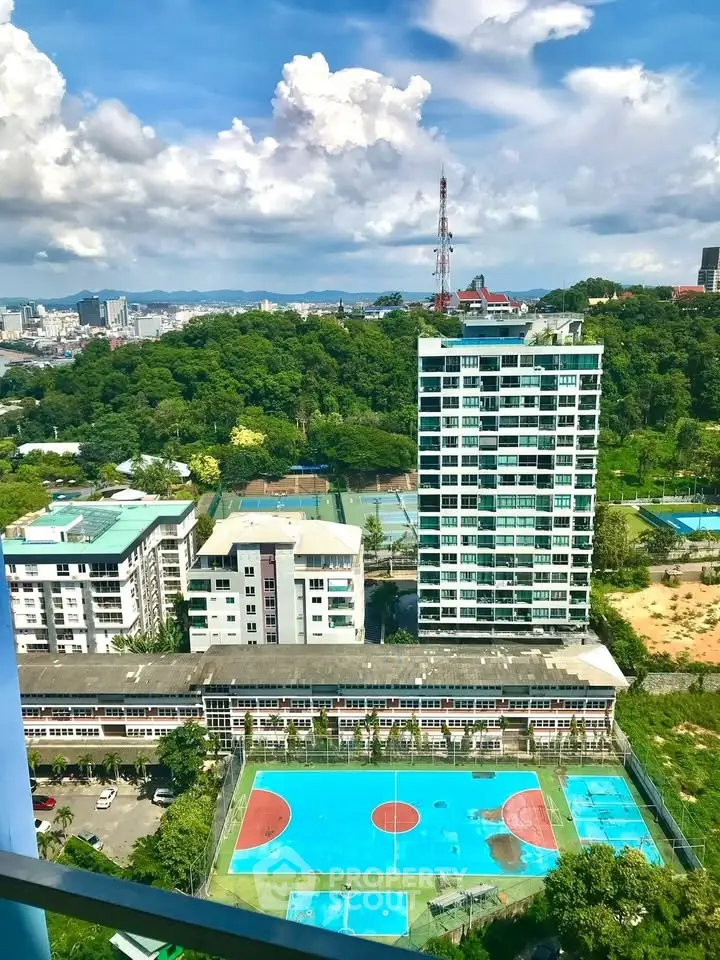 Stunning high-rise view of modern apartment complex with sports courts and lush greenery.