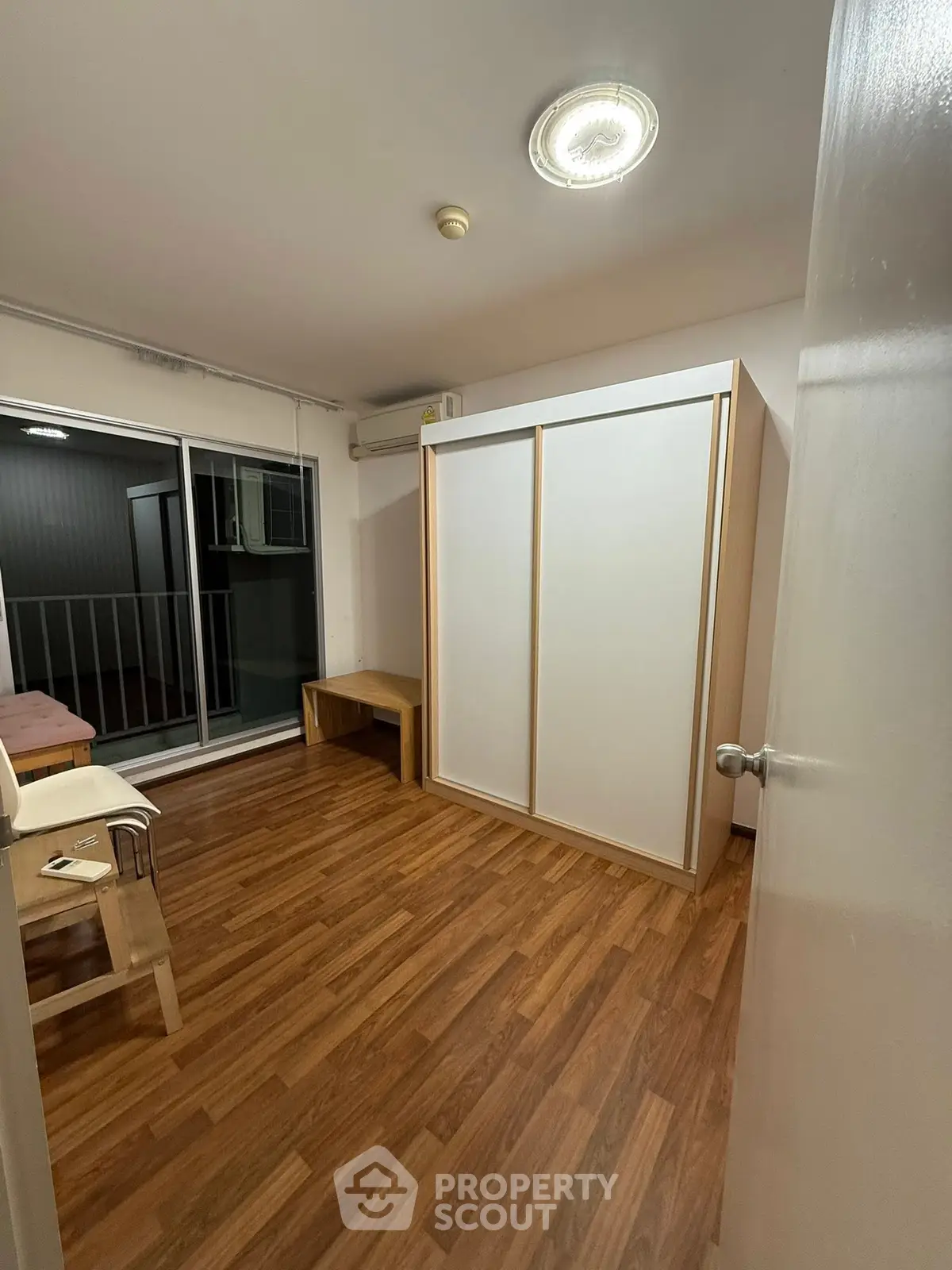 Spacious bedroom with wooden flooring and sliding wardrobe doors, featuring a balcony view.
