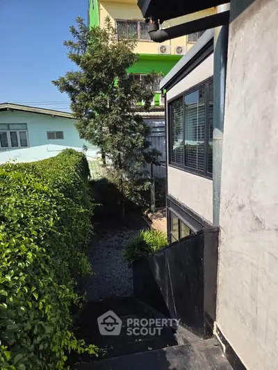 Charming exterior view of a modern building with lush greenery and a serene pathway.