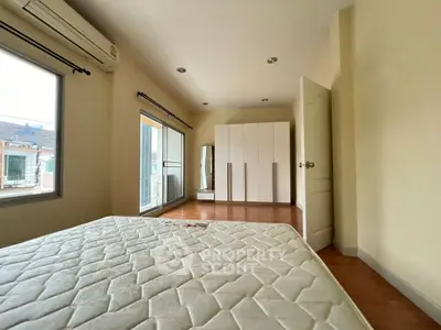 Spacious bedroom with large windows and modern wardrobe in a bright, airy setting.
