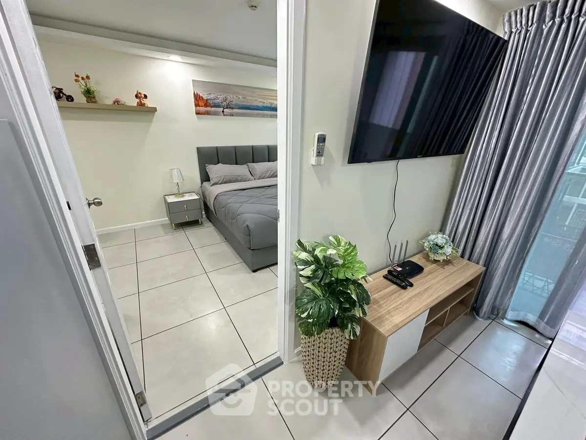 Modern bedroom with sleek decor and large TV, perfect for urban living.