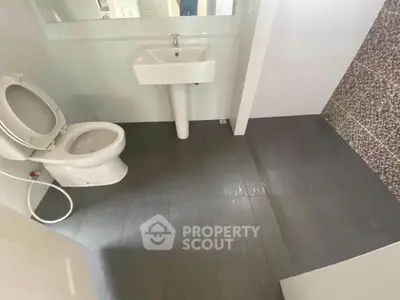 Modern bathroom with sleek design and tiled flooring, featuring a pedestal sink and toilet.