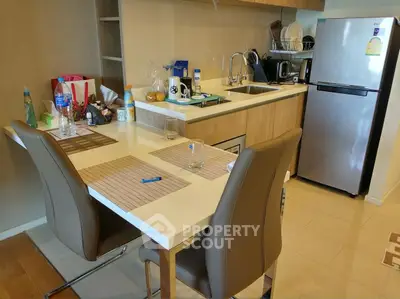 Modern kitchen with sleek appliances and dining area in stylish apartment.