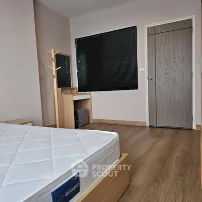 Modern bedroom with wooden flooring and stylish furniture, featuring a comfortable mattress and sleek window blinds.