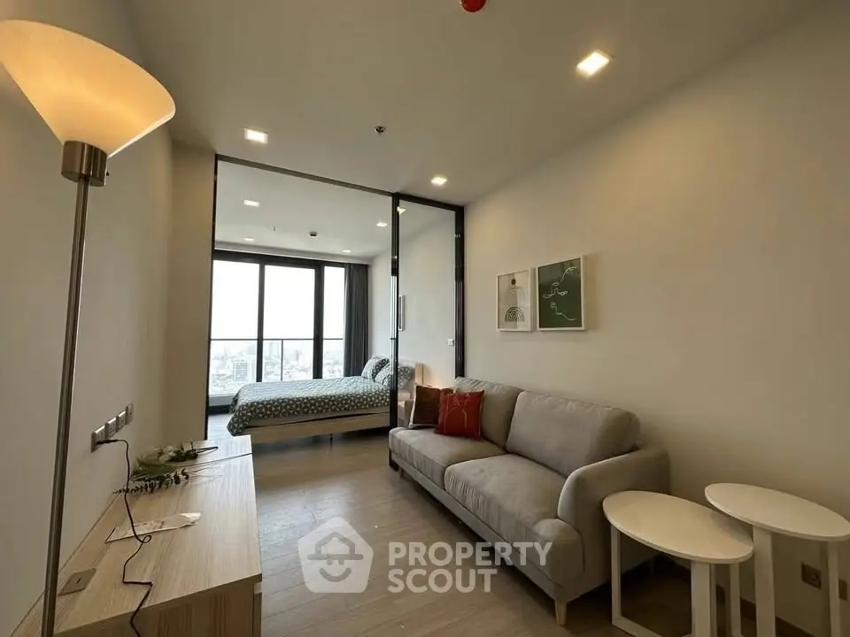 Modern living room with cozy sofa and view into stylish bedroom