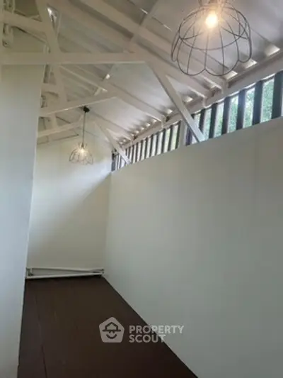Charming attic space with modern lighting and wooden flooring, perfect for creative use.