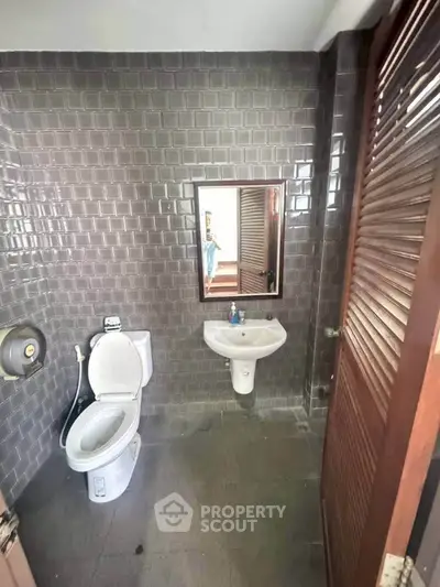 Modern bathroom with sleek gray tiles and compact fixtures.