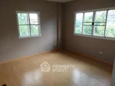 Spacious empty room with large windows and wooden flooring, ideal for customization.