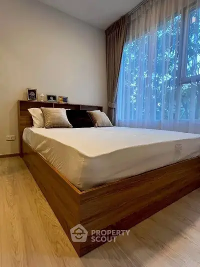 Cozy bedroom with wooden bed frame and large window with curtains