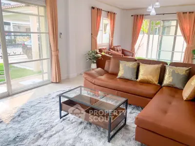 Spacious living room with modern brown leather sofa and glass coffee table, featuring large windows and elegant curtains.