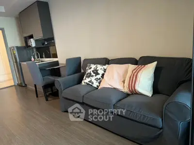 Modern living room with cozy sofa and compact kitchen in open layout apartment.