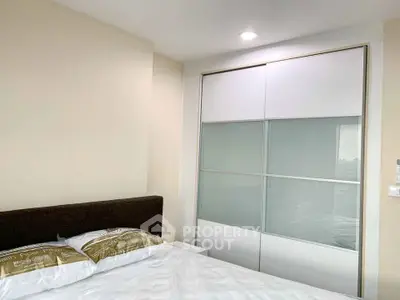 Modern bedroom with sleek sliding closet doors and cozy bed setup.