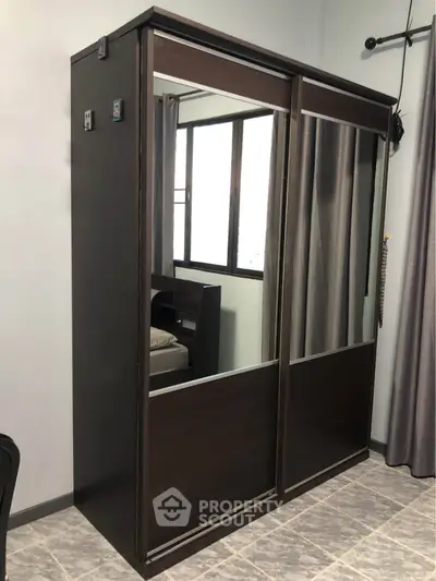 Modern bedroom with sleek mirrored wardrobe and large window for natural light.