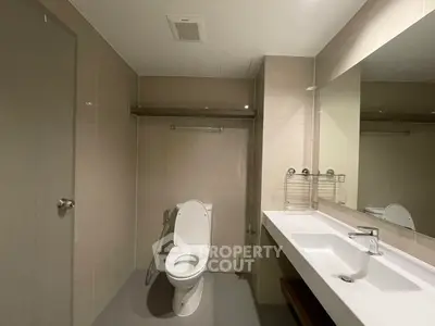 Modern bathroom with sleek fixtures and large mirror in contemporary apartment.