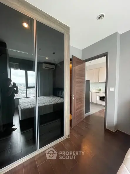 Modern bedroom with mirrored wardrobe and view into sleek kitchen
