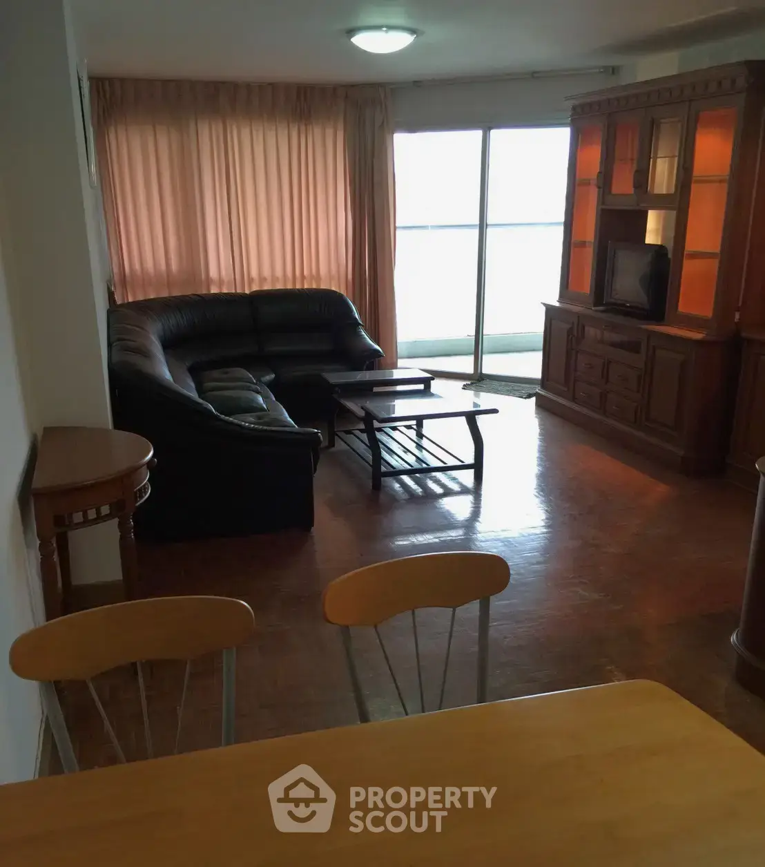 Spacious living room with elegant wooden furniture and large windows for natural light.