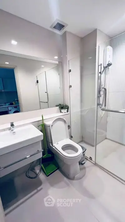 Modern bathroom with glass shower and sleek fixtures in contemporary apartment.