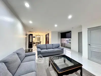 Spacious modern living room with elegant gray sofas and sleek glass coffee table.