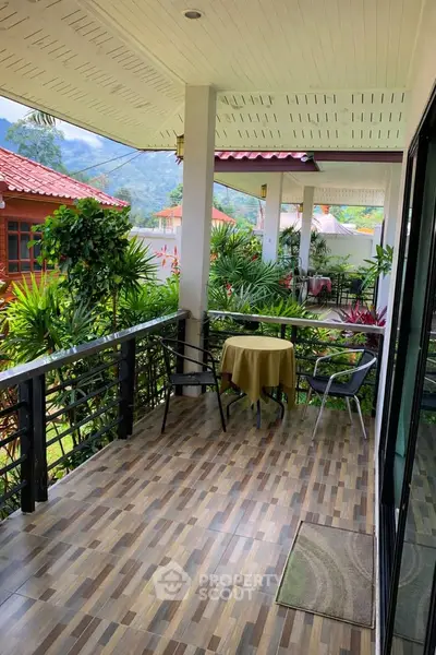 Charming balcony with lush garden view and cozy seating area, perfect for relaxation.