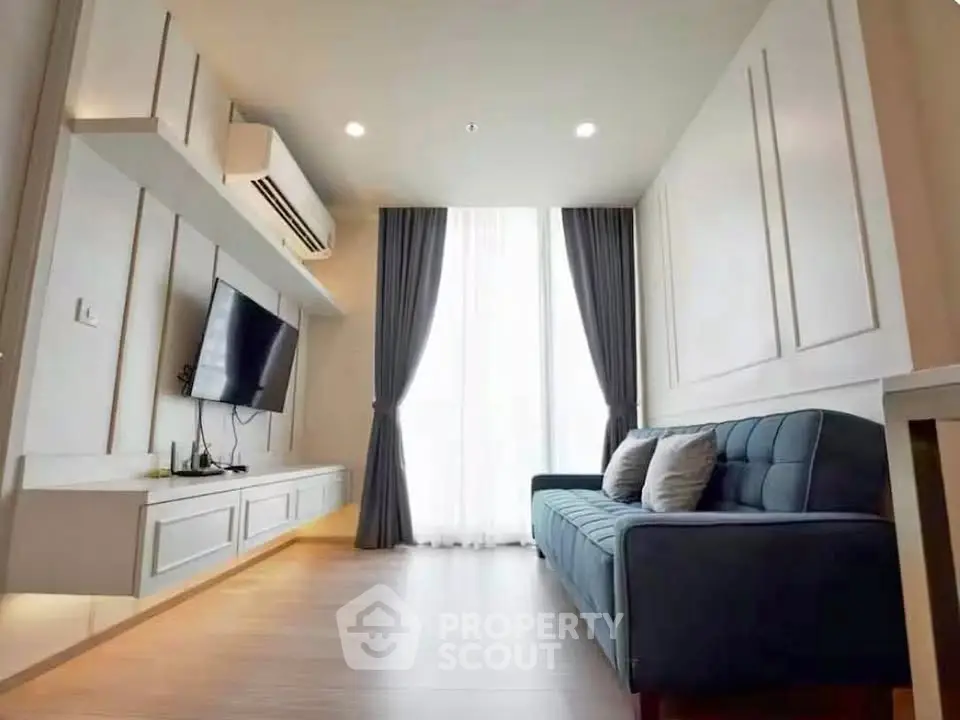 Modern living room with sleek design, featuring a wall-mounted TV and elegant curtains.