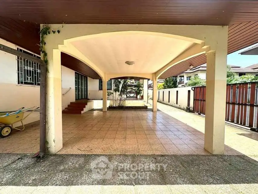 Spacious covered patio with tiled flooring and garden view, perfect for outdoor gatherings.