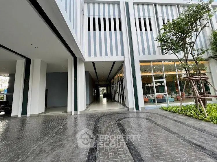 Modern building entrance with sleek design and landscaped surroundings, showcasing contemporary architecture.
