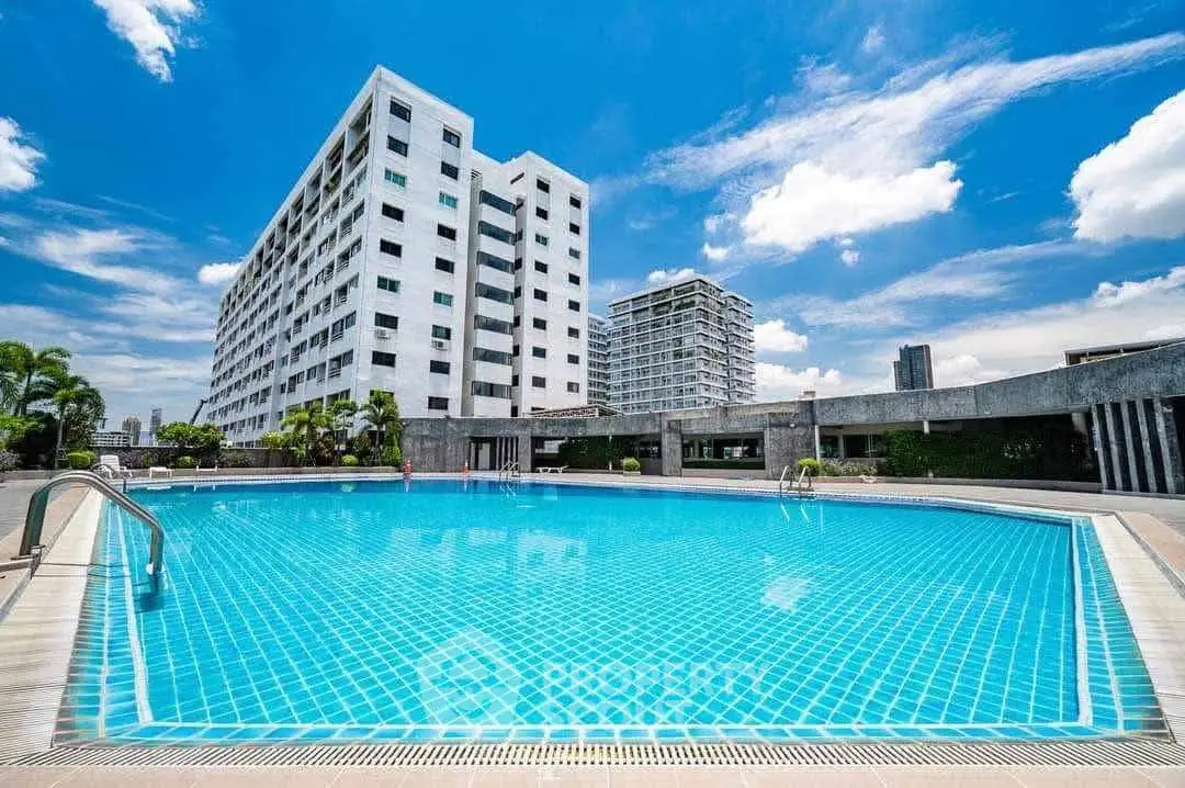 Luxurious condominium with a stunning outdoor pool and modern architecture under a clear blue sky.