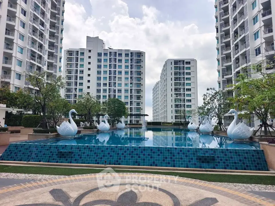 Luxurious condominium complex with stunning pool and elegant swan sculptures, offering a serene urban oasis.