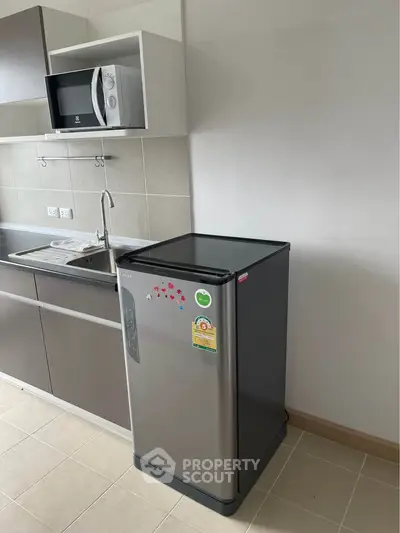 Modern kitchen with compact fridge and microwave in sleek apartment