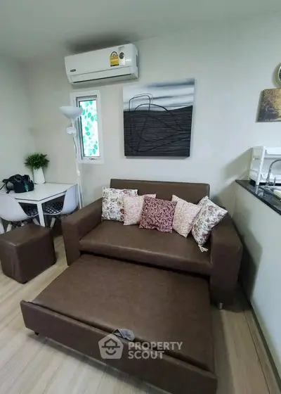 Cozy living room with brown sofa bed, modern decor, and air conditioning in a stylish apartment.