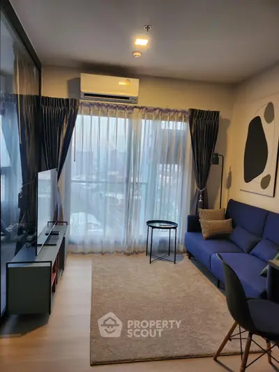 Modern living room with blue sofa, large window, and stylish decor in a cozy apartment.