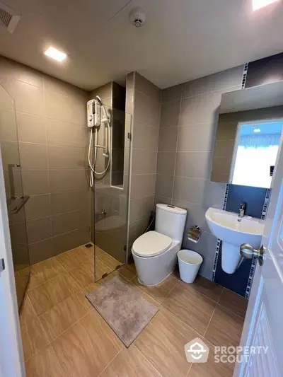 Modern bathroom with glass shower and sleek fixtures in contemporary home.