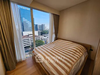 Cozy bedroom with large window offering stunning city view in modern apartment.