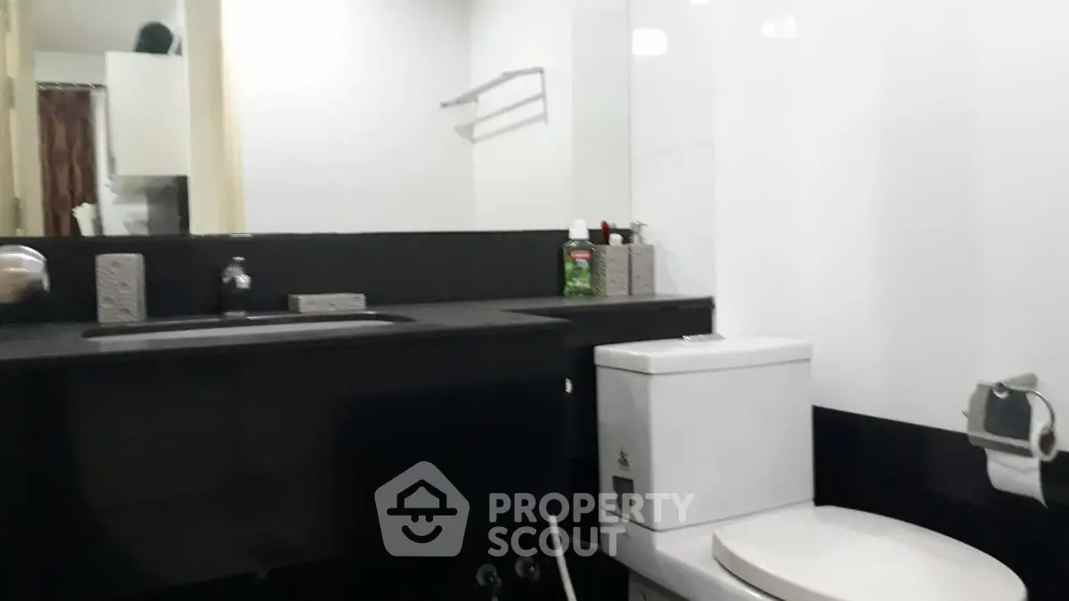 Modern bathroom with sleek black and white design featuring a toilet and sink.