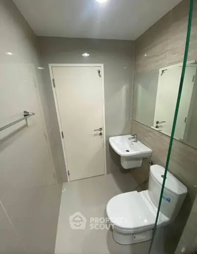 Modern bathroom with sleek fixtures and neutral tiles, featuring a wall-mounted sink and toilet.