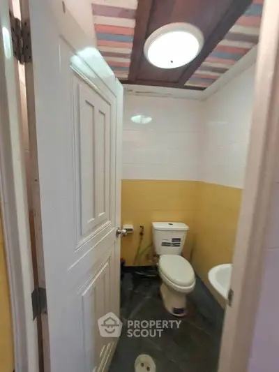 Compact bathroom with modern fixtures and bright yellow accent wall.