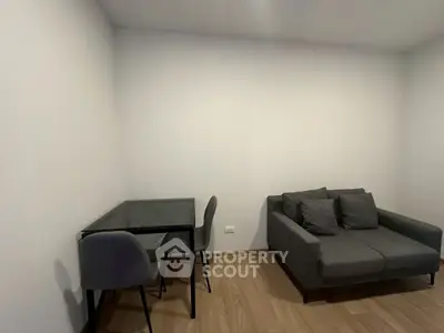 Modern minimalist living room with sleek gray sofa and glass dining table, perfect for urban living.