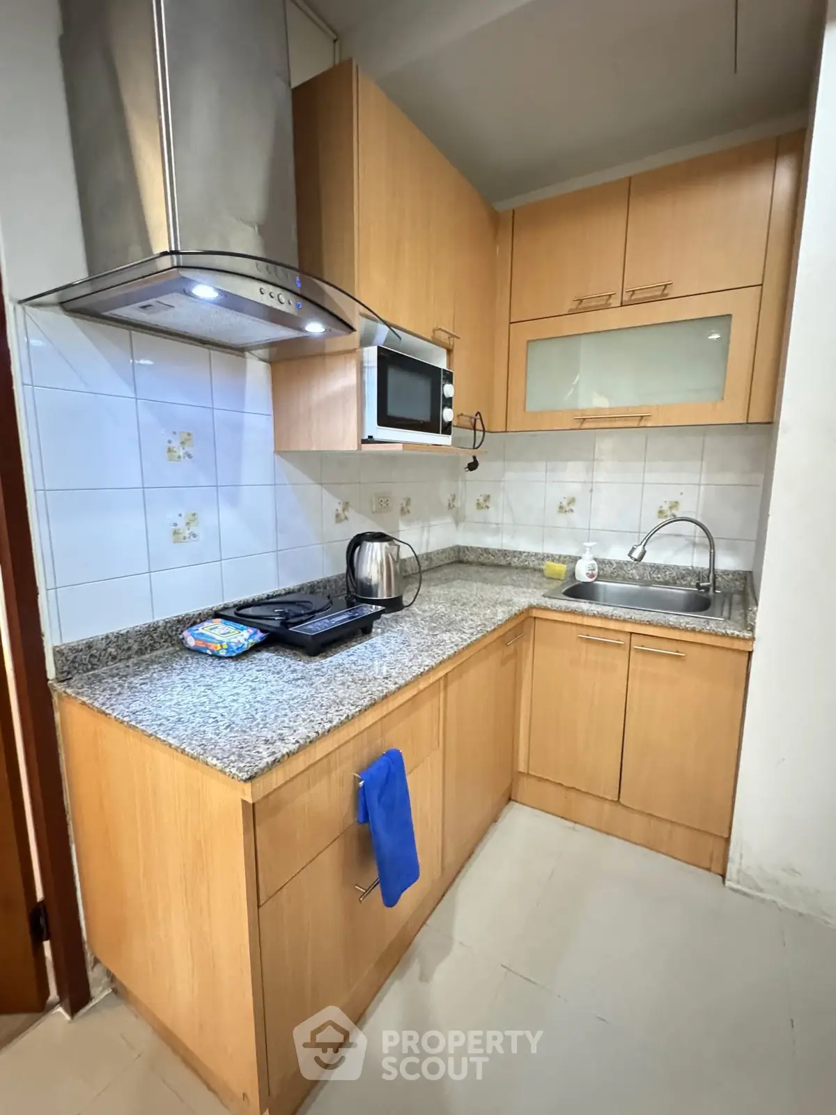 Modern kitchen with granite countertops and wooden cabinets, featuring a microwave and stainless steel range hood.