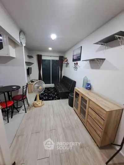 Cozy living room with modern decor and balcony access, featuring a stylish sofa and sleek wooden flooring.