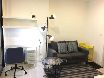 Modern living room with stylish sofa, floor lamp, and workspace area in a cozy apartment.