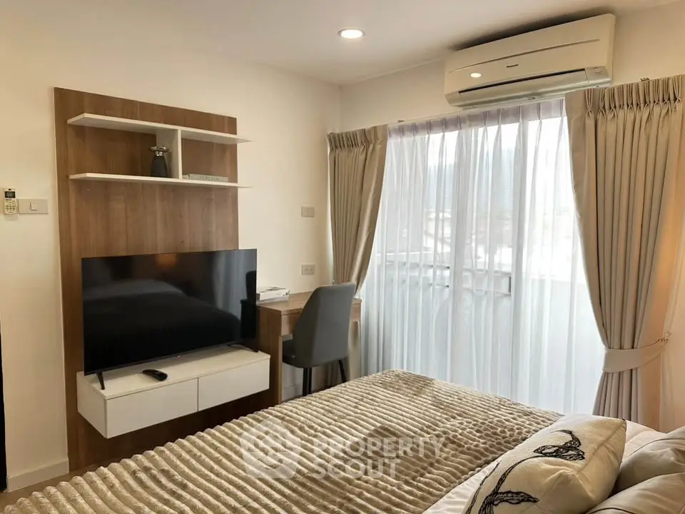 Cozy bedroom with modern decor and natural light from large window.
