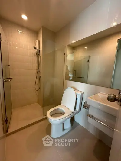 Modern bathroom with glass shower and sleek fixtures in contemporary apartment.