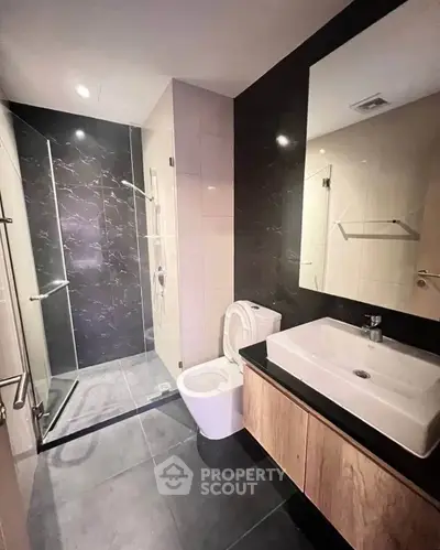 Modern bathroom with sleek design, featuring a glass shower and stylish vanity.