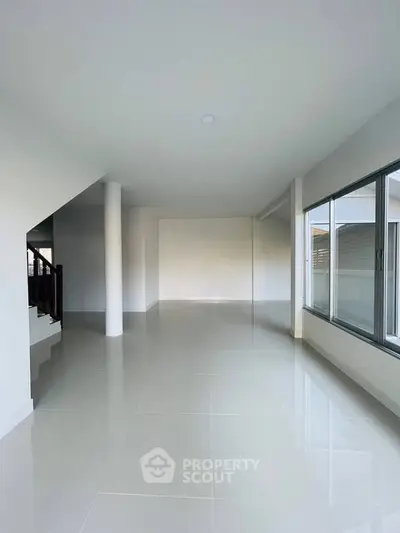 Spacious modern living room with large windows and glossy tiled floors